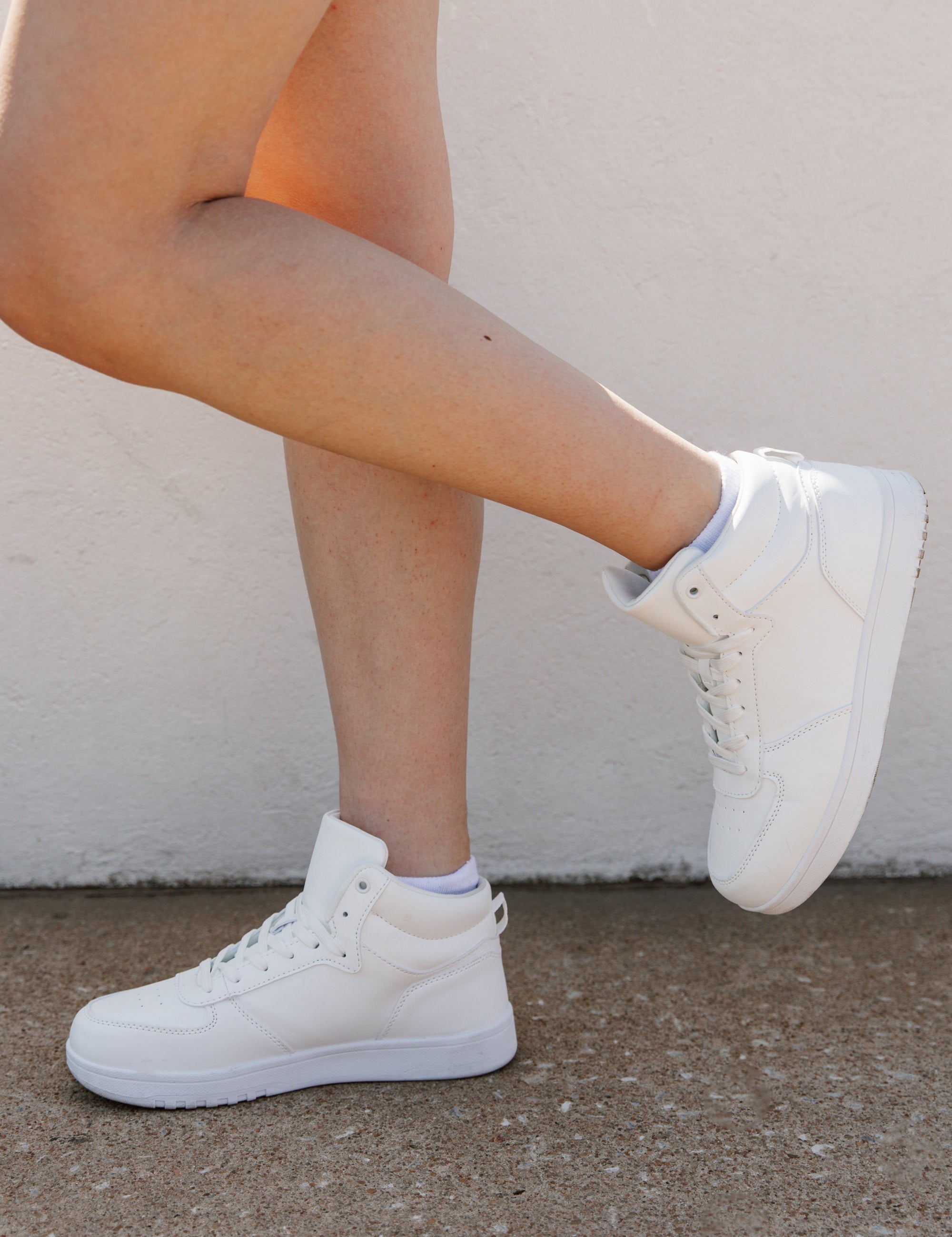 White Step Up Midtop Sneakers - Side Angle On Model | Gameday Couture - SOHO
